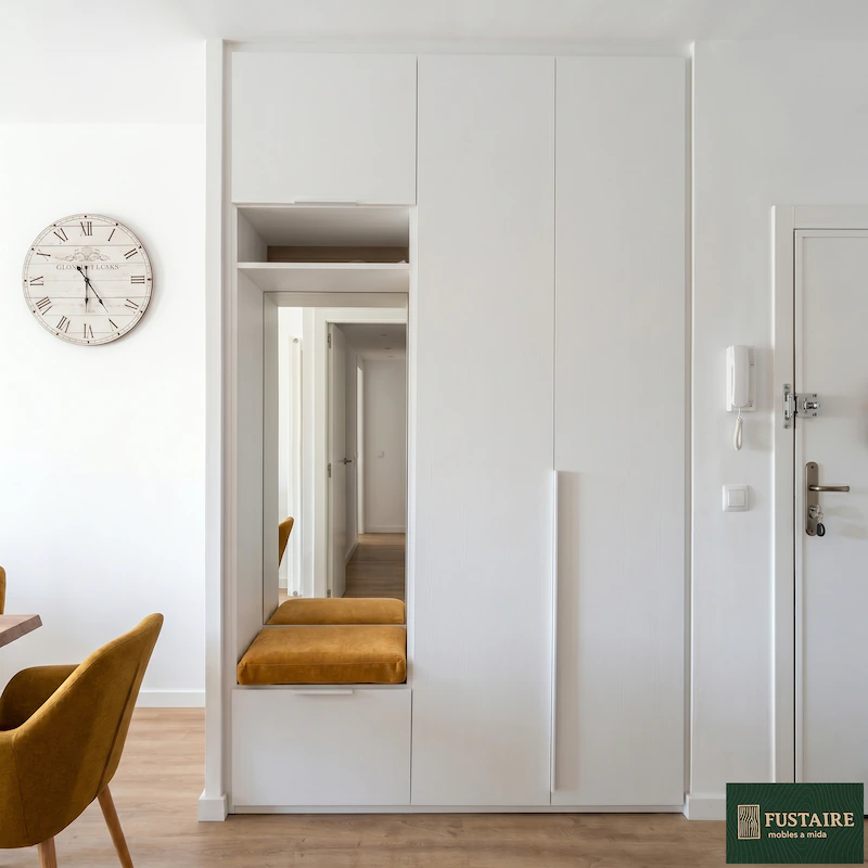 Mueble recibidor a medida de suelo a techo en color blanco texturizado con armario ropero, espejo vertical y banco descalzador tapizado en color mostaza fabricado por Fustaire en Barcelona